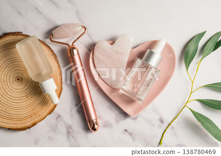 Rose quartz gua sha tool and face massage roller on wooden tray, beauty abstract photo. Top view Rose quartz gua sha tool and face massage roller on wooden tray, beauty abstract photo. Top view 138780469
