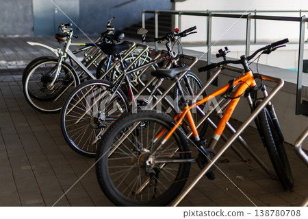 Row of parked bicycles with diverse frames in morning sunlight under protective shelter Row of parked bicycles with diverse frames in morning sunlight under protective shelter 138780708