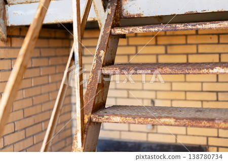 Corroded urban fire escape. Textured exterior staircase with flaking rust and gritty details 138780734