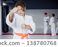 Young girl in gi sparring with focus, lively training environment of dojo 138780768