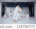 Young judo students practice throws in modern dojo with coach supervising 138780772