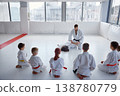 Children seated in semicircle focusing on instructor demonstrating techniques 138780779