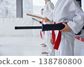 Children lining up holding foam bat before judo class in bright studio 138780800