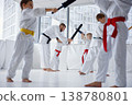 Instructor adjusting child stance with bokken during close coaching session 138780801