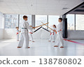 Paired children practicing partner drills with bokken in bright dojo 138780802