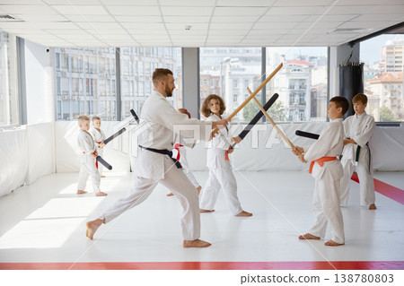 Children practicing karate with bokken under instructor guidance 138780803