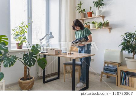 Woman repairing old clothes for sustainable fashion. Woman sewing torn denim jeans at home workshop workplace. Promoting upcycling, slow fashion, and circular economy concepts 138780867