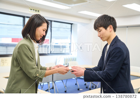 會議室裡,一男一女兩位商務人士微笑著交換名片。 會議室裡,一男一女兩位商務人士微笑著交換名片。 138780872