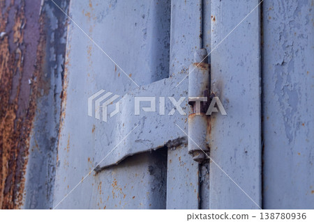 Close-up view of a garage door hinge showing signs of rust and wear in an outdoor environment during daytime Close-up view of a garage door hinge showing signs of rust and wear in an outdoor environment during daytime 138780936
