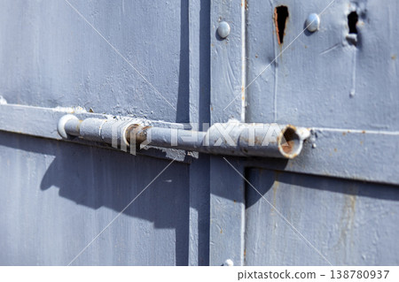 A close-up view of a garage lock on a metal door shows signs of rust and wear. The lock is part of a security system used to secure the garage 138780937