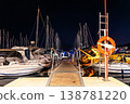 Night marina pier between moored yachts under dark starry sky navigation lights reflecting calm water. Harbor dock perspective boats masts ropes walkway travel luxury sailing lifestyle atmosphere 138781220