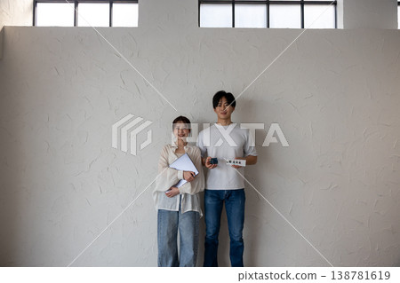 一對年輕男女站在牆前,手裡拿著電子電路和一台電腦。 一對年輕男女站在牆前,手裡拿著電子電路和一台電腦。 138781619