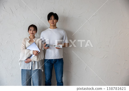 一對年輕男女站在牆前，手裡拿著電子電路和一台電腦。 138781621