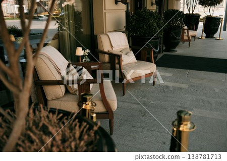 Elegant outdoor seating area with armchairs, plants and soft decor near hotel building entrance in Belgrade. Concept of comfort, hospitality and premium lifestyle Elegant outdoor seating area with armchairs, plants and soft decor near hotel building entrance in Belgrade. Concept of comfort, hospitality and premium lifestyle 138781713