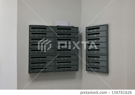 Set of metal mailboxes mounted on white wall inside residential building hallway. Concept of communication, delivery, apartment living and everyday infrastructure 138781826