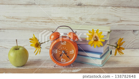 Back to school still life with books, flowers, alarm clock and apple on wooden background. Colorful school still life. 138782648