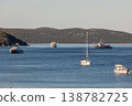 Calm sea bay with scattered vessels yacht sailboat motorboat naval ship green island clear sky evening sunlight. Tranquil coastal landscape travel freedom relaxation and peaceful maritime atmosphere 138782725