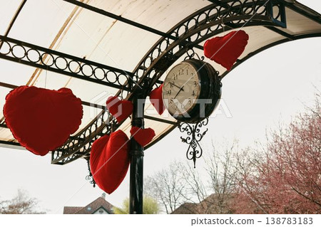 Vintage street clock under metal canopy decorated with red hearts in Stanisici Ethno Village near Bijeljina Bosnia and Herzegovina. Concept of romance tourism decoration and travel destination 138783183