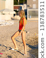 Young teenager girl colorful braids wear cap orange rashguard walk along sandy beach waterline warm golden sunlight. Summer seaside lifestyle teen child explore nature vacation Adriatic coast Croatia 138783511