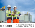 Field engineers speaking and reviewing data on tablet at oil refinery worksite 138783751