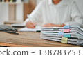 A person is sitting at a desk with a stack of papers in front of them 138783753