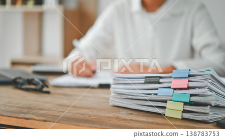 A person is sitting at a desk with a stack of papers in front of them 138783753