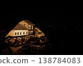 Illuminated houses stand on a hillside in Mostar during a quiet night. Warm interior lights contrast with deep shadows and reveal traditional stone architecture 138784083