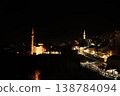 Night view of the historic old town in Mostar with illuminated stone houses, mosque minarets, riverside cafes and warm lights reflecting along the Neretva River 138784094