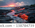 Lava from a volcano flows into the ocean while sunset colors the sky and waves crash on the shore in Hawaii 138784739