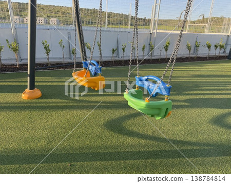 Playground swings on artificial grass under sunny sky, suitable for childrens activity background Playground swings on artificial grass under sunny sky, suitable for childrens activity background 138784814
