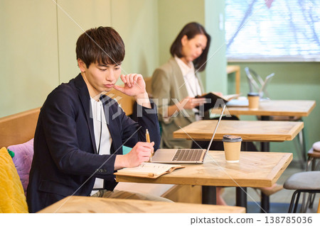 A man and a woman working on their laptops in a cafe-style co-working space. A man and a woman working on their laptops in a cafe-style co-working space. 138785036