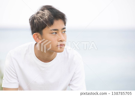 一幅男學生凝視遠方的肖像畫，背景是大海。 138785705