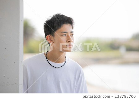 A male student in a white T-shirt looks relaxed outdoors. A male student in a white T-shirt looks relaxed outdoors. 138785706