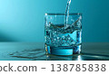 Refreshing water pouring into a clear glass against a soothing blue background, showcasing  138785838