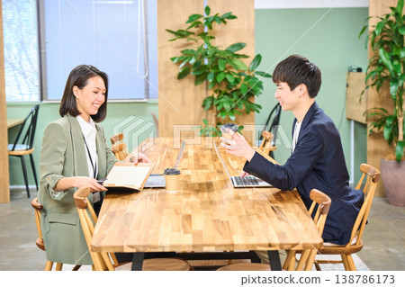 一對男女商務人士在免費辦公地址的辦公室裡一邊喝咖啡一邊聊天。 一對男女商務人士在免費辦公地址的辦公室裡一邊喝咖啡一邊聊天。 138786173