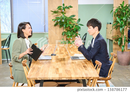 Business professionals, a man and a woman, chatting over coffee in a free-address office. 138786177