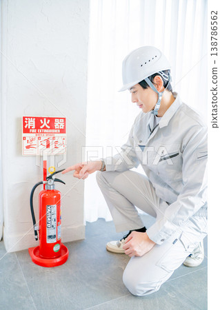一名身穿工作服的男子正在檢查消防安全設備。 一名身穿工作服的男子正在檢查消防安全設備。 138786562
