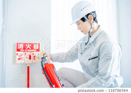 一名身穿工作服的男子正在檢查消防安全設備。 一名身穿工作服的男子正在檢查消防安全設備。 138786564