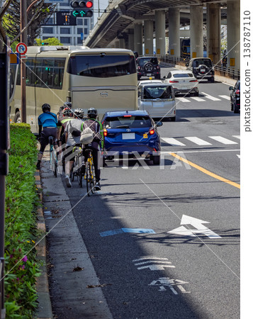 A group of cyclists waiting for a car turning left on a bicycle navigation lane: Traffic rules and safety challenges at intersections. A group of cyclists waiting for a car turning left on a bicycle navigation lane: Traffic rules and safety challenges at intersections. 138787110