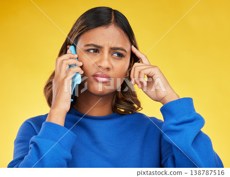 Confused, phone call and young woman in a studio with an unsure, doubt or thinking facial expression. Technology, remember and Indian female model on a mobile conversation by a yellow background. Confused, phone call and young woman in a studio with an unsure, doubt or thinking facial expression. Technology, remember and Indian female model on a mobile conversation by a yellow background. 138787516