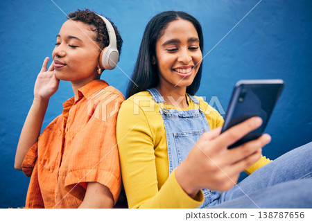 Phone, music and women in city on blue background online for social media, internet and streaming audio. Friendship, happy and female people relax on smartphone listening to song, track and radio 138787656