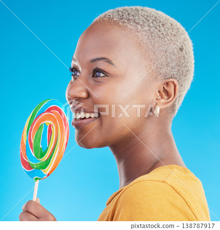 Lollipop, thinking and a woman with candy in studio for sweets, rainbow and creative idea. Profile of happy black female person isolated on a blue background with sugar, freedom and smile or color Lollipop, thinking and a woman with candy in studio for sweets, rainbow and creative idea. Profile of happy black female person isolated on a blue background with sugar, freedom and smile or color 138787917