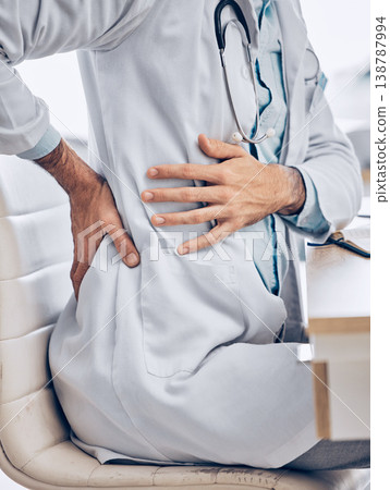 Man, doctor and hands with back pain from injury, accident or posture sitting on chair at the hospital. Closeup of male person, medical or healthcare employee with sore spine, ache or cramp at clinic Man, doctor and hands with back pain from injury, accident or posture sitting on chair at the hospital. Closeup of male person, medical or healthcare employee with sore spine, ache or cramp at clinic 138787994