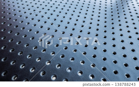 Macro view of a dark blue or black perforated metal sheet with a repetitive circular hole pattern Macro view of a dark blue or black perforated metal sheet with a repetitive circular hole pattern 138788243