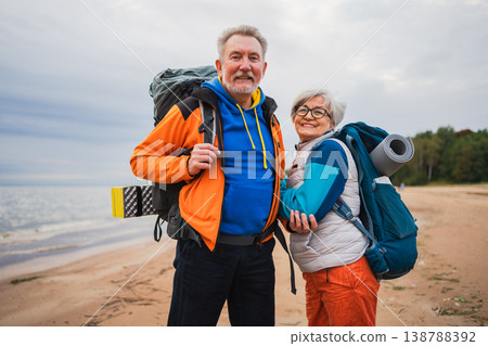 Hiking tourism adventure. Senior couple man woman enjoying outdoor recreation hiking on beach. Happy old people backpackers hikers enjoy walking hike trekking tourism active vacation beauty of nature Hiking tourism adventure. Senior couple man woman enjoying outdoor recreation hiking on beach. Happy old people backpackers hikers enjoy walking hike trekking tourism active vacation beauty of nature 138788392