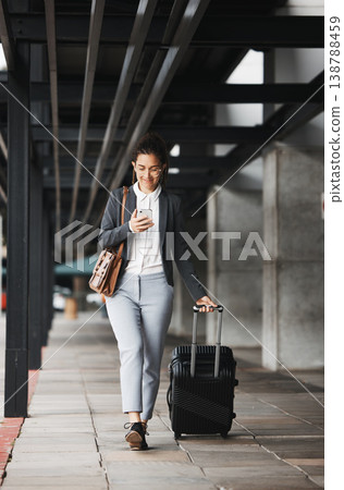 Phone, travel and suitcase with a business woman walking in an airport parking lot outdoor in the city. Mobile, luggage and commute with a young female employee on an international trip for work Phone, travel and suitcase with a business woman walking in an airport parking lot outdoor in the city. Mobile, luggage and commute with a young female employee on an international trip for work 138788459