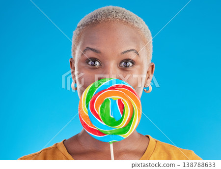 Candy, lollipop and portrait a woman in studio for wow sweets, rainbow and creative advertising. Happy black female person isolated on a blue background with sugar, freedom and color surprise 138788633