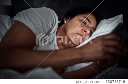 Insomnia, night and phone with old woman in bed for social media, thinking and communication. Tired, fatigue and relax with senior person in bedroom at home for mobile app, streaming and contact 138788746