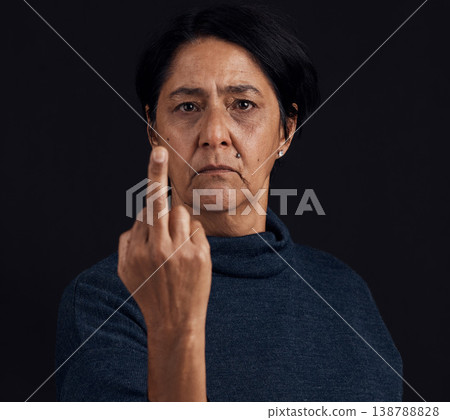 Portrait, anger and senior woman with middle finger, opinion and expression on a black studio background. Face, female person and old model with gesture, rude and frustrated with problem and conflict 138788828
