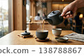 A close-up of someone pouring warm tea from a teapot, evoking the image of a tea time at a modern Japanese-style cafe. 138788867